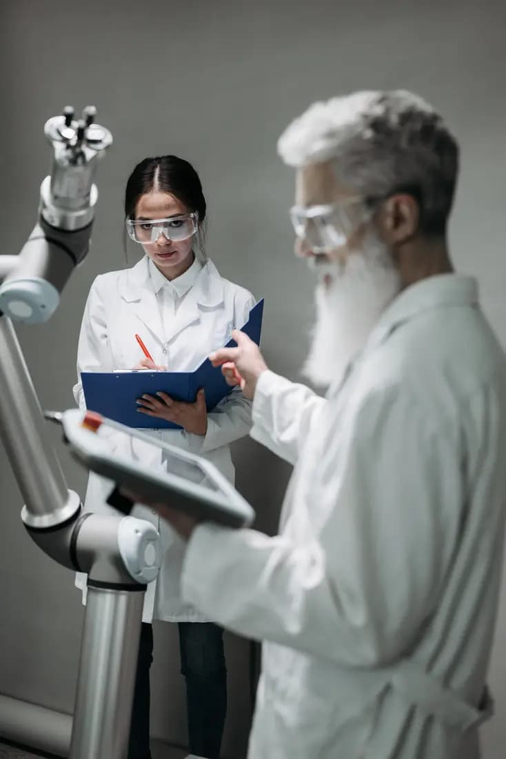 Researchers working alongside a robotic arm in a lab